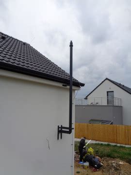 Pracovník merajúci komín pred oplechovaním