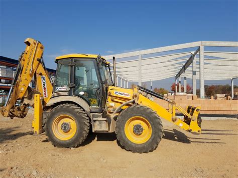 Traktorbagr s hydraulickým kladivom v akcii
