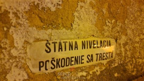 Stará smaltovaná tabuľka s nápisom „Štátna nivelácia, poškodenie sa trestá“ na fasáde budovy