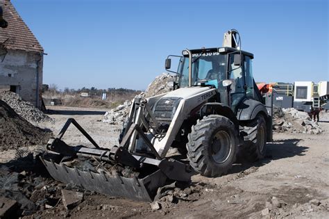Traktorbager s pripojeným búracím kladivom