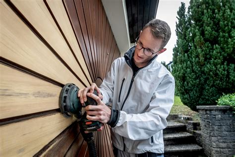 Pracovník s respirátorom a ochrannými okuliarmi pri brúsení dreva