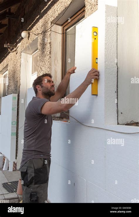 Man working with level at thermal insulation of the facade