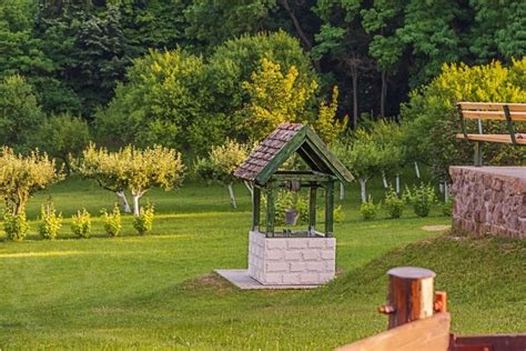 Dekoratívna studňa obložená tehlovými pásikmi v záhrade