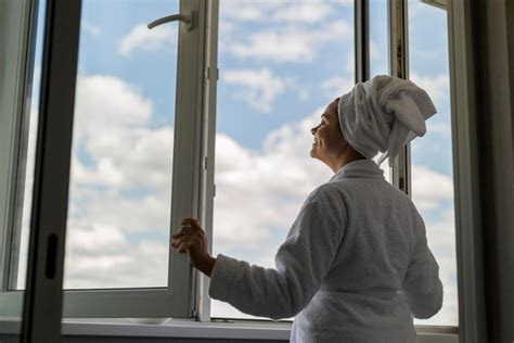 Žena v teplom huňatom župane pri okne s horúcou čokoládou